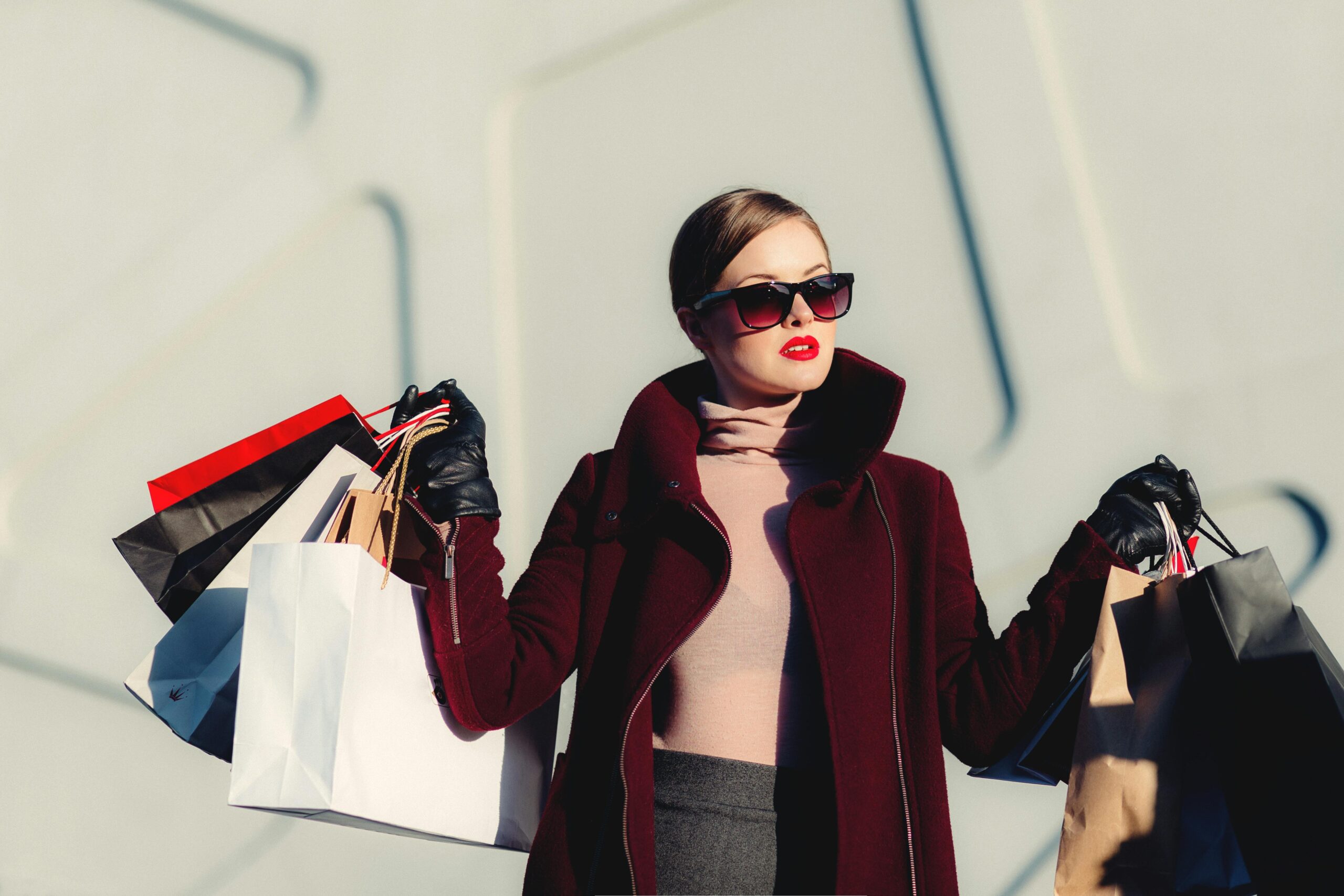 Stylish young woman in sunglasses carrying shopping bags outdoors. Elegant fashion statement.